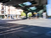 a street with two trains on it and a few people walking under an overpass