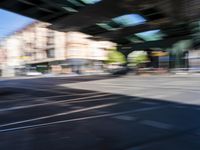 a street with two trains on it and a few people walking under an overpass