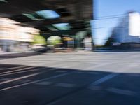 a street with two trains on it and a few people walking under an overpass