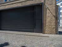 two windows in the side of a brick building, with a black garage door and brown door