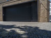 two windows in the side of a brick building, with a black garage door and brown door