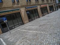 the sidewalk is paved with stones and has a bench in front of it, with no people inside