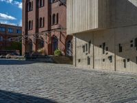 cobblestone driveway surrounded by modern buildings on sunny day with sun reflecting onto the windows