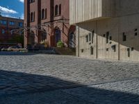 cobblestone driveway surrounded by modern buildings on sunny day with sun reflecting onto the windows