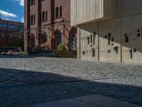 cobblestone driveway surrounded by modern buildings on sunny day with sun reflecting onto the windows