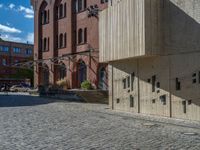 cobblestone driveway surrounded by modern buildings on sunny day with sun reflecting onto the windows