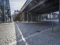 a city street under an overpass on a sunny day with sunlight shining down the street