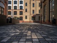 a sidewalk with chairs next to the brick building on the side, some have stairs and some buildings in the background