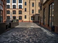 a sidewalk with chairs next to the brick building on the side, some have stairs and some buildings in the background