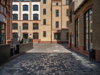 a sidewalk with chairs next to the brick building on the side, some have stairs and some buildings in the background