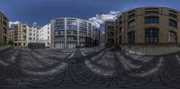 a panoramic shot of some buildings and a walkway in the foreground are circular