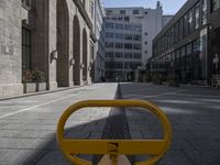 a yellow bench on the side of the road near tall buildings in an urban setting