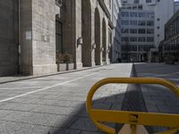 a yellow bench on the side of the road near tall buildings in an urban setting