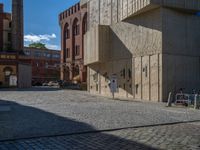 cobblestone driveway surrounded by modern buildings on sunny day with sun reflecting onto the windows