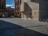 cobblestone driveway surrounded by modern buildings on sunny day with sun reflecting onto the windows