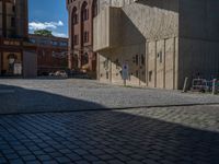 cobblestone driveway surrounded by modern buildings on sunny day with sun reflecting onto the windows