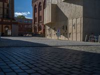 cobblestone driveway surrounded by modern buildings on sunny day with sun reflecting onto the windows