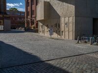 cobblestone driveway surrounded by modern buildings on sunny day with sun reflecting onto the windows