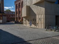 cobblestone driveway surrounded by modern buildings on sunny day with sun reflecting onto the windows