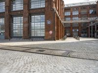 a cobblestone parking spot outside an old building with a sign that says u and the ground is brick