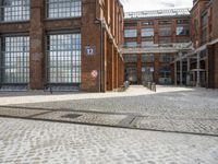 a cobblestone parking spot outside an old building with a sign that says u and the ground is brick