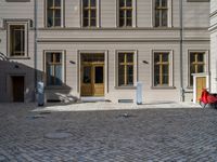 an empty parking lot with plants in the ground and on the side of the building, there is an enclosed area and windows