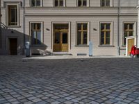 an empty parking lot with plants in the ground and on the side of the building, there is an enclosed area and windows