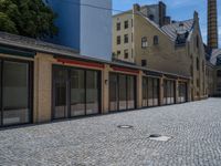 the sidewalk is paved with stones and has a bench in front of it, with no people inside