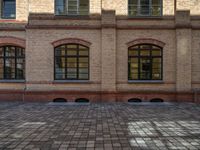 a sidewalk with chairs next to the brick building on the side, some have stairs and some buildings in the background