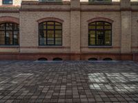 a sidewalk with chairs next to the brick building on the side, some have stairs and some buildings in the background