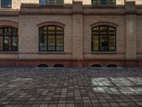 a sidewalk with chairs next to the brick building on the side, some have stairs and some buildings in the background