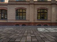 a sidewalk with chairs next to the brick building on the side, some have stairs and some buildings in the background