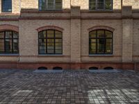 a sidewalk with chairs next to the brick building on the side, some have stairs and some buildings in the background