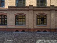 a sidewalk with chairs next to the brick building on the side, some have stairs and some buildings in the background