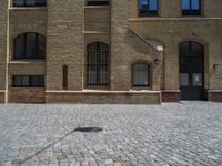 the sidewalk is paved with stones and has a bench in front of it, with no people inside