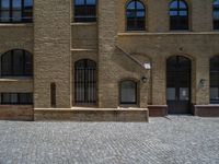 the sidewalk is paved with stones and has a bench in front of it, with no people inside