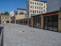 the sidewalk is paved with stones and has a bench in front of it, with no people inside