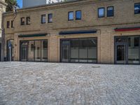 the sidewalk is paved with stones and has a bench in front of it, with no people inside