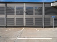 an empty parking lot with metal roller shutter doors and a stop sign on the corner