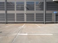 an empty parking lot with metal roller shutter doors and a stop sign on the corner