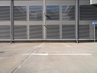 an empty parking lot with metal roller shutter doors and a stop sign on the corner