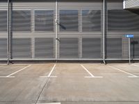 an empty parking lot with metal roller shutter doors and a stop sign on the corner