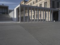 a building is shown with several columns surrounding it and a sign above it on the sidewalk