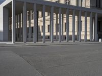 a building is shown with several columns surrounding it and a sign above it on the sidewalk