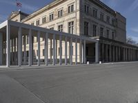 a building is shown with several columns surrounding it and a sign above it on the sidewalk