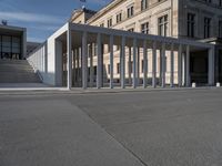 a building is shown with several columns surrounding it and a sign above it on the sidewalk