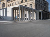 a building is shown with several columns surrounding it and a sign above it on the sidewalk