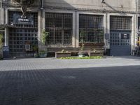 an empty parking lot in an urban area with windows and benches to sit and relax on