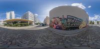 a fish eye lens is view of a building on the left and graffiti on the right