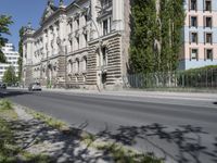 a person is riding a bike on the side of the road next to a large building